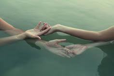 two hands reaching for each other in the water