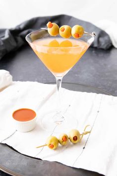 a martini with olives in it on a tray next to saucers and napkin