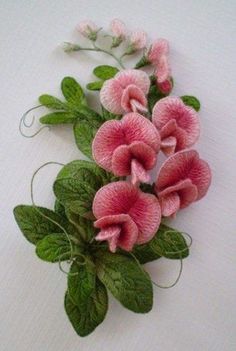 some pink flowers and green leaves on a white surface