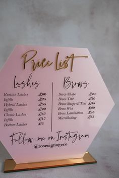 a pink price list sign with gold writing on it's front and back sides