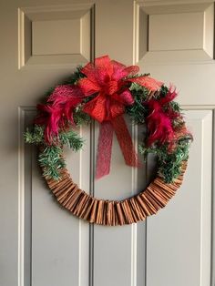 a wreath is hanging on the front door with red and green decorations, as well as a bow