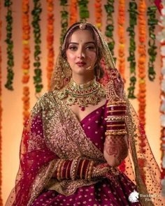 a woman in a red and gold bridal outfit with her hands on her hip