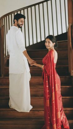 a man and woman holding hands while standing on stairs