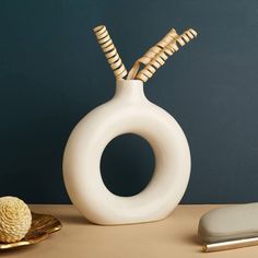 a white vase sitting on top of a table next to a gold plated object