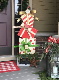 a christmas decoration on the front steps of a house with presents wrapped in paper and bows