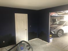 a car is parked in the garage next to a door with a vacuum on it