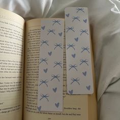 two bookmarks with blue hearts on them are laying next to an open book