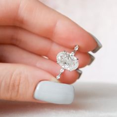 a woman's hand holding a ring with a white diamond on the middle finger