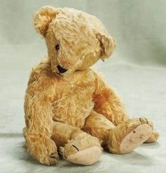 a brown teddy bear sitting on the ground