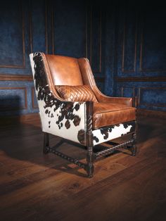 a brown and white chair sitting on top of a hard wood floor next to a blue wall