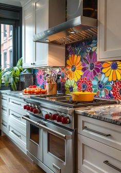 a kitchen with colorful flowers on the backsplash and stainless steel oven hoods