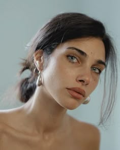 a close up of a woman wearing earrings and looking off to the side with her hand on her hip