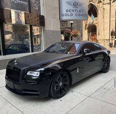 a black rolls royce parked in front of a building