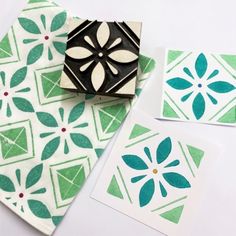 some green and white paper with designs on them next to a rubber stamp that has been placed on top of it