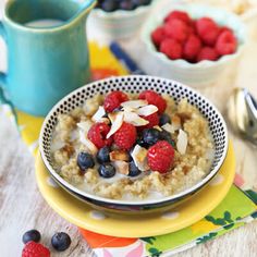 a bowl of oatmeal with berries and blueberries on the side next to a spoon