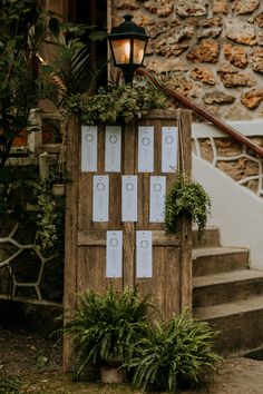 a wooden door is decorated with greenery and seating cards for guests to sit in