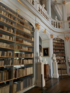 a room filled with lots of books next to a tall white wall covered in gold trim