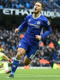 a soccer player is running with the ball in front of him and people watching from the stands