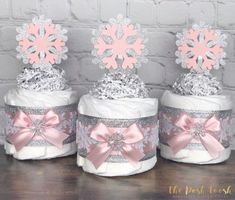 three diaper cakes decorated with pink and silver snowflakes