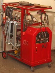 a small red machine sitting on top of a metal cart next to a white wall