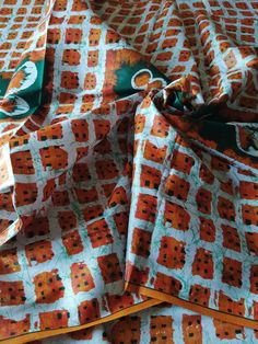 an orange and green patterned fabric on a bed