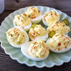 deviled eggs on a plate with pickles and seasoning