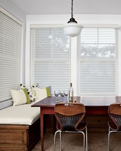 two chairs and a table in a room with white blinds on the windowsills