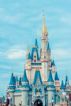 the castle is blue and has gold spires on it's roof, while people are standing in front of it