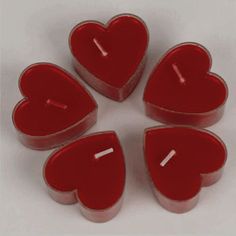 four red heart shaped candles sitting on top of each other