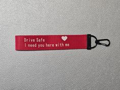 a red keychain that says drive safe, i need you here with me