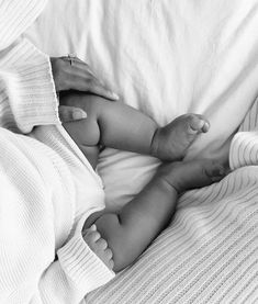 a black and white photo of a woman holding a baby in her arms while laying on a bed