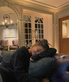 a woman laying on top of a couch with her eyes closed and head resting on a pillow