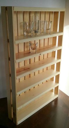 a wooden shelf filled with glasses on top of a table