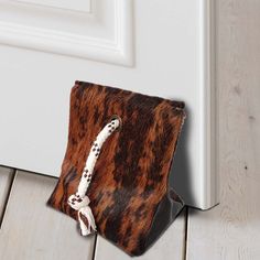 a brown and white animal print pouch sitting on top of a wooden floor next to a door