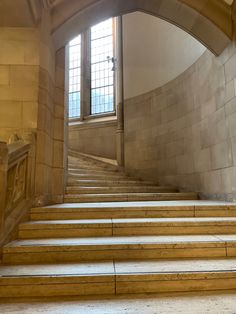 the stairs are made of wood and have stone treadmings on each side, leading up to an arched window