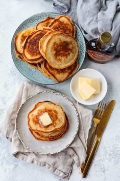 pancakes with butter and syrup on a plate next to a fork, knife and spoon