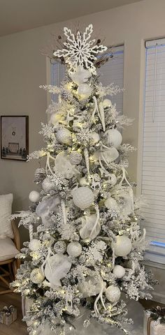 a white christmas tree decorated with ornaments and snowflakes