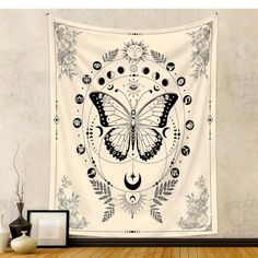 a wall hanging tapestry with a butterfly and moon design on the front in black and white