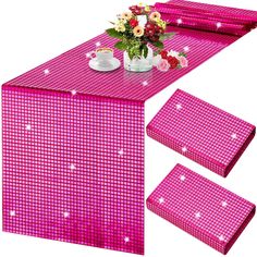 a table with pink cloths and flowers on it, next to two place mats