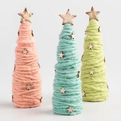 three small christmas trees made out of yarn and gold stars on each one, all in different colors