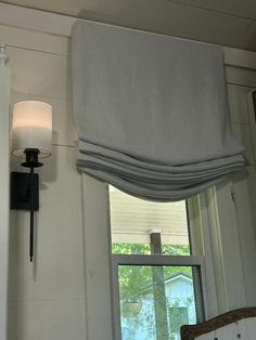 a bathroom with a window and white towels hanging on the wall above it, next to a light fixture