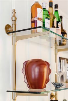 a glass shelf with bottles and glasses on it