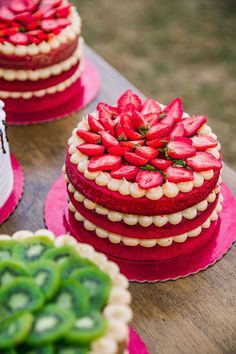 red and white cakes on pink plates sitting on top of a wooden table next to each other