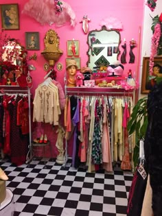 a pink room filled with lots of clothes and accessories on display next to a black and white checkered floor