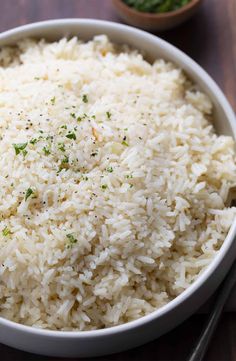 a white bowl filled with rice on top of a wooden table