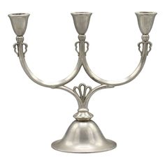 a metal candelabra with two candles on it's sides and one candle holder in the shape of a bell