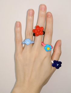 a person's hand with three rings on it and two flowers in the middle