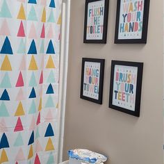 three framed pictures on the wall above a toilet in a bathroom with a colorful shower curtain