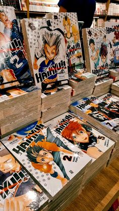 many anime books are on display in a book store with people looking at the covers