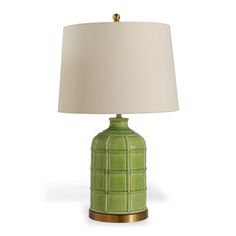 a green table lamp with a white shade on the top and gold trim around the base